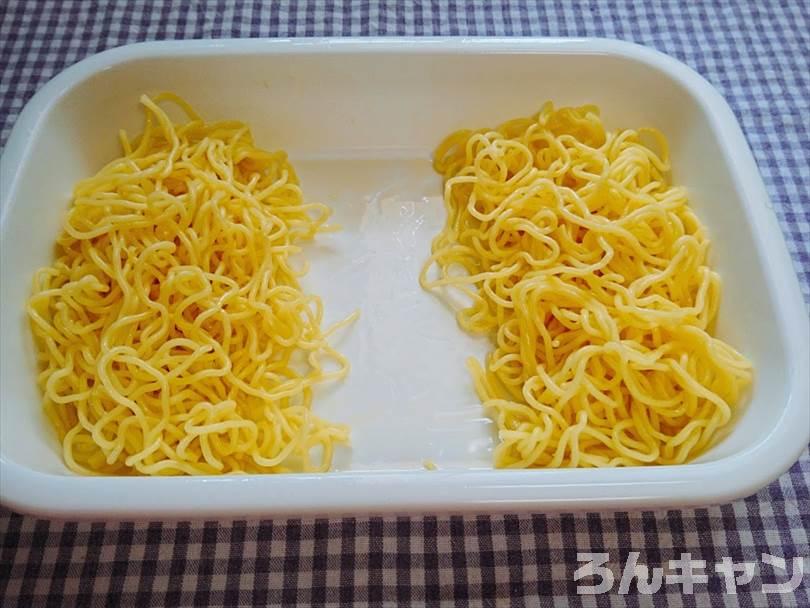 バットに焼きそばの麺を入れてごま油であえたものを半分に分ける