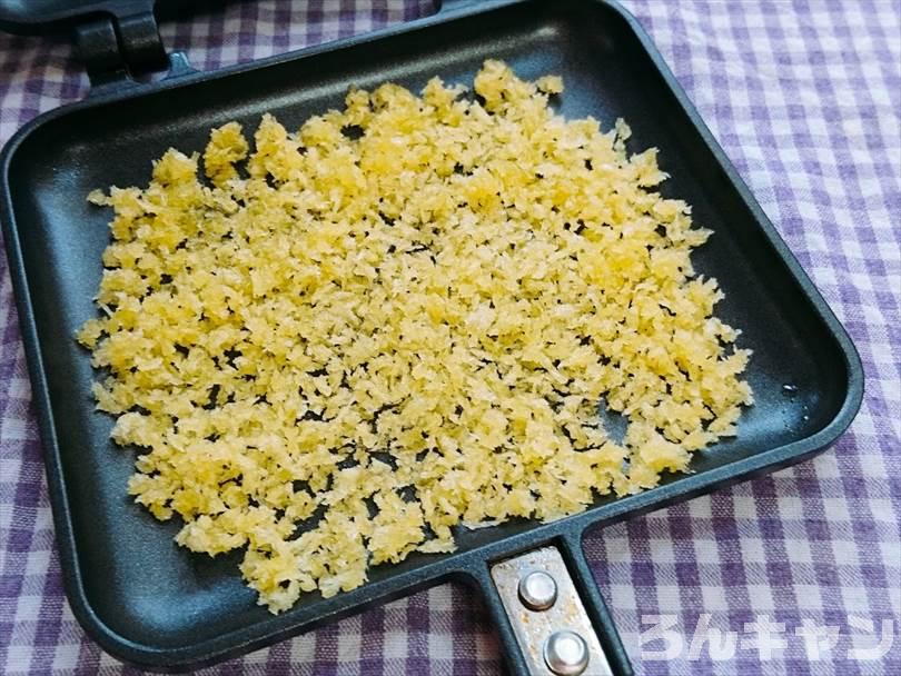 ホットサンドメーカーにオリーブオイルをかけて混ぜでたパン粉をのせる